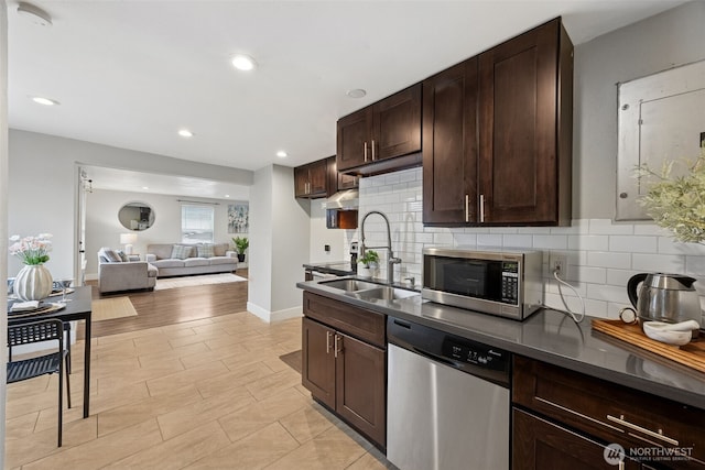 kitchen with stainless steel appliances, dark countertops, a sink, and dark brown cabinets