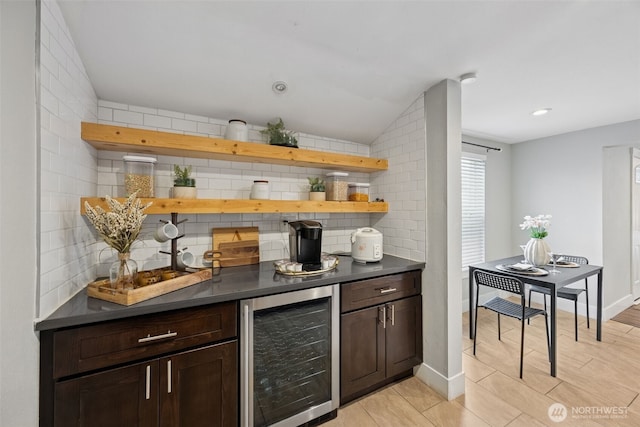 bar featuring beverage cooler, baseboards, vaulted ceiling, backsplash, and a dry bar