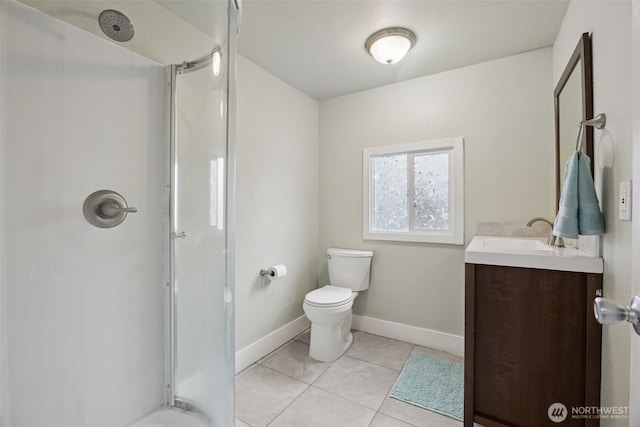 bathroom featuring toilet, a stall shower, vanity, baseboards, and tile patterned floors