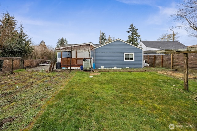 rear view of house featuring a fenced backyard, a deck, and a yard