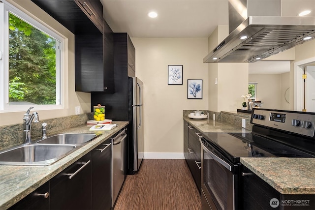 11752 35th Ave NE, Seattle, WA 98125 - kitchen with stainless steel appliances, wall chimney range hood, a sink, dark cabinets, and baseboards