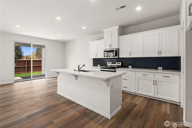 kitchen with a kitchen island with sink, visible vents, white cabinetry, light countertops, and appliances with stainless steel finishes