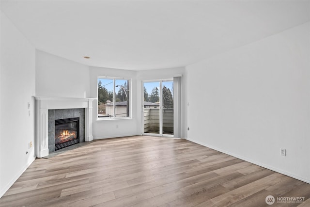 unfurnished living room with a fireplace, light wood-style flooring, and baseboards