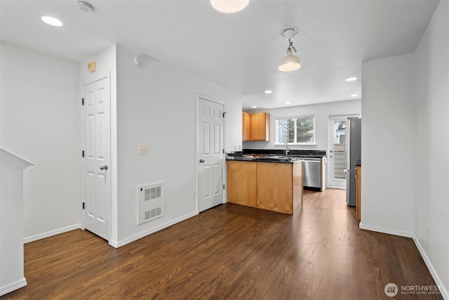 kitchen featuring dark countertops, baseboards, stainless steel appliances, and dark wood-style flooring