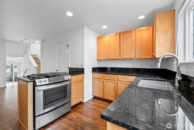 kitchen featuring recessed lighting, a sink, stainless steel gas range, dark stone countertops, and dark wood finished floors