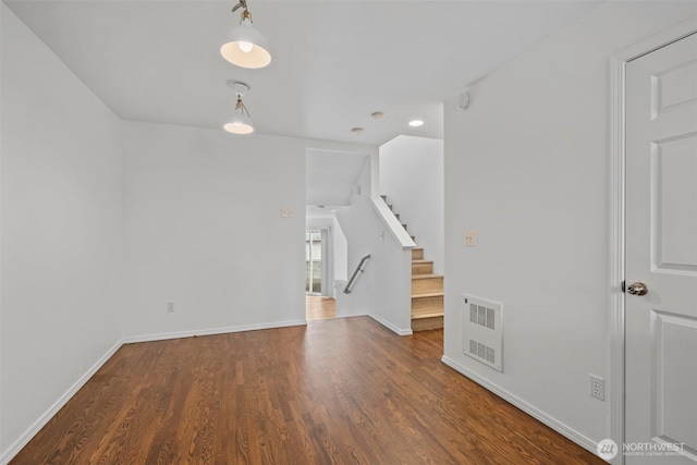 unfurnished living room with dark wood-style floors, visible vents, stairway, and baseboards