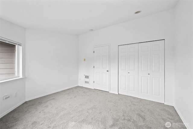 unfurnished bedroom featuring carpet flooring, visible vents, and baseboards