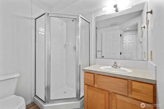 bathroom featuring a stall shower, visible vents, decorative backsplash, toilet, and vanity