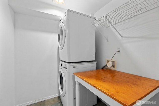 laundry room featuring laundry area, stacked washer and clothes dryer, and baseboards