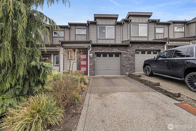 view of property featuring a garage, stone siding, driveway, and board and batten siding