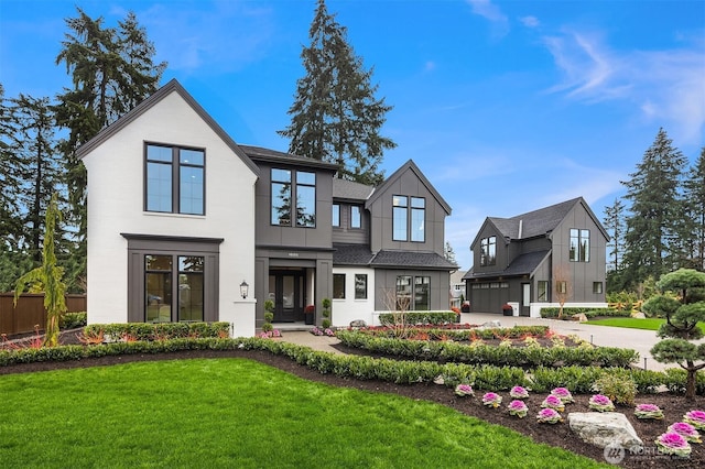 rear view of property featuring an attached garage, fence, driveway, a yard, and board and batten siding