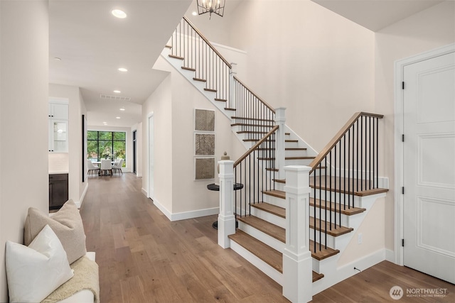 staircase featuring recessed lighting, visible vents, an inviting chandelier, wood finished floors, and baseboards