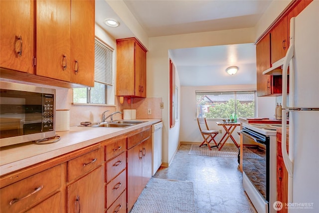 kitchen featuring light countertops, backsplash, brown cabinetry, a sink, and white appliances