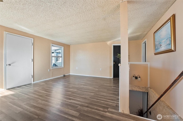 unfurnished room featuring a textured ceiling, wood finished floors, and baseboards