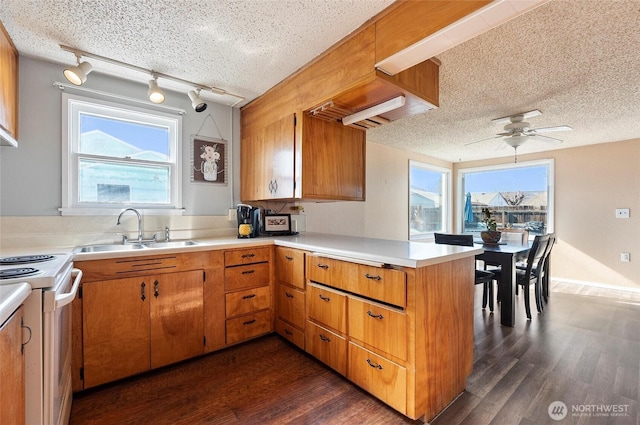 kitchen featuring a peninsula, light countertops, a sink, and white electric range oven