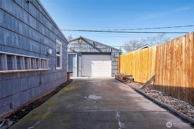 exterior space with a garage, driveway, an outdoor structure, and fence