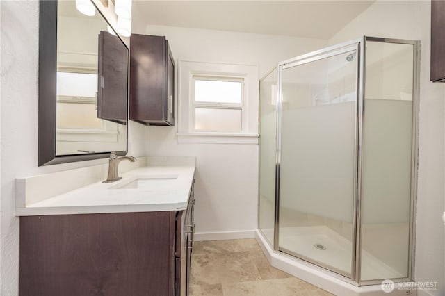 full bathroom with a stall shower, baseboards, and vanity