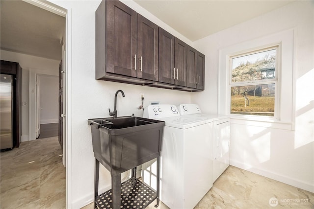 washroom featuring marble finish floor, washing machine and clothes dryer, cabinet space, and baseboards