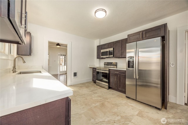 kitchen with dark brown cabinetry, a sink, visible vents, light countertops, and appliances with stainless steel finishes