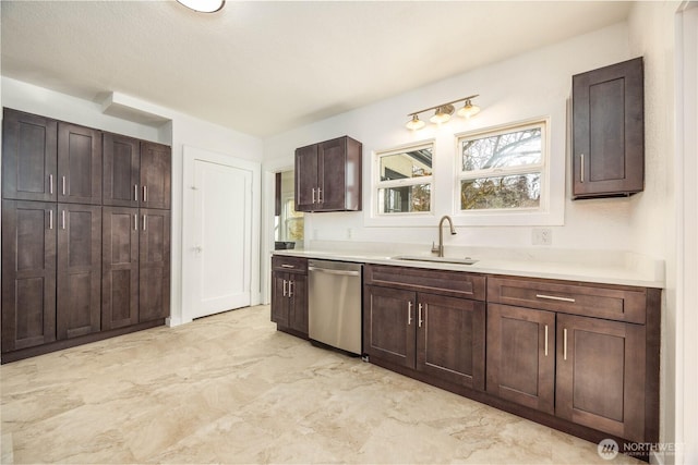 kitchen featuring dark brown cabinetry, a sink, marble finish floor, light countertops, and stainless steel dishwasher