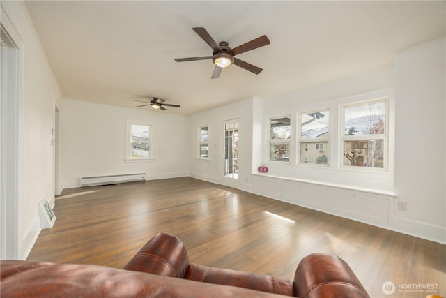 unfurnished living room with baseboard heating, dark wood finished floors, and baseboards