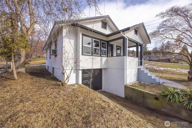 view of side of property featuring an attached garage and stucco siding