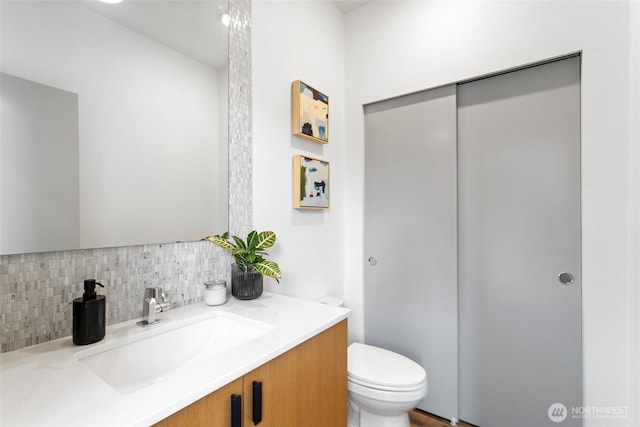 half bathroom with tasteful backsplash, vanity, and toilet