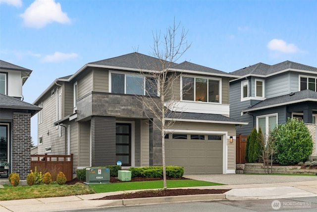 prairie-style home with driveway, a shingled roof, and an attached garage