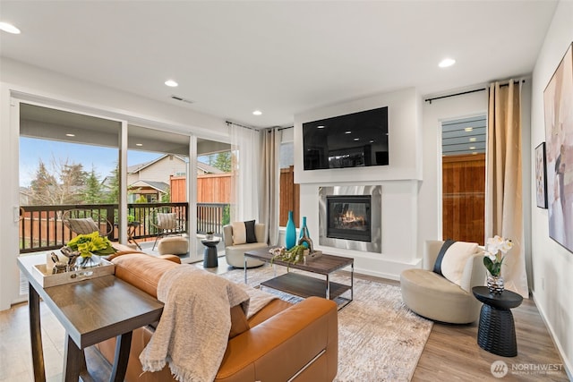 living room featuring a fireplace, wood finished floors, visible vents, and recessed lighting