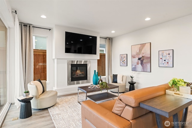 living room with recessed lighting, wood finished floors, and a glass covered fireplace