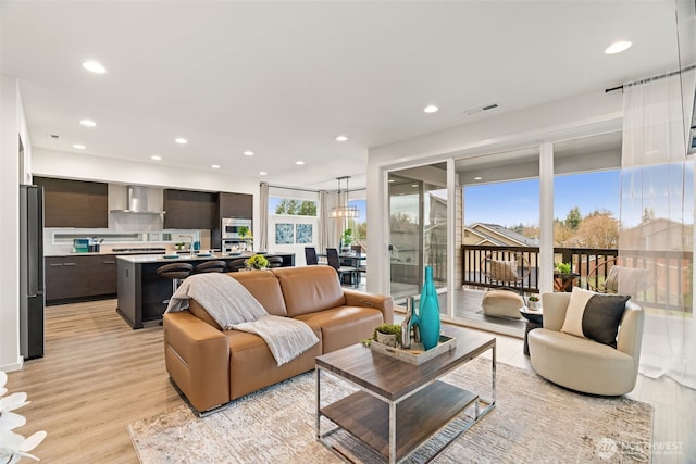 living area with a chandelier, light wood finished floors, visible vents, and recessed lighting