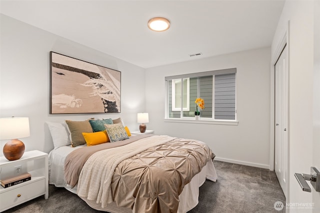 bedroom with a closet, dark carpet, visible vents, and baseboards