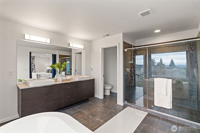 full bathroom featuring toilet, a sink, visible vents, and a shower stall