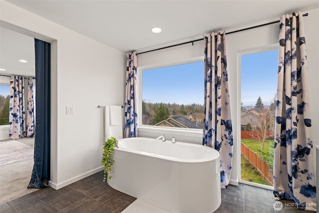 bathroom with a wealth of natural light, baseboards, a freestanding bath, and recessed lighting