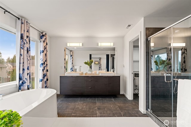 bathroom with double vanity, a stall shower, visible vents, a freestanding tub, and a sink