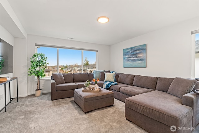 living area featuring light carpet and baseboards