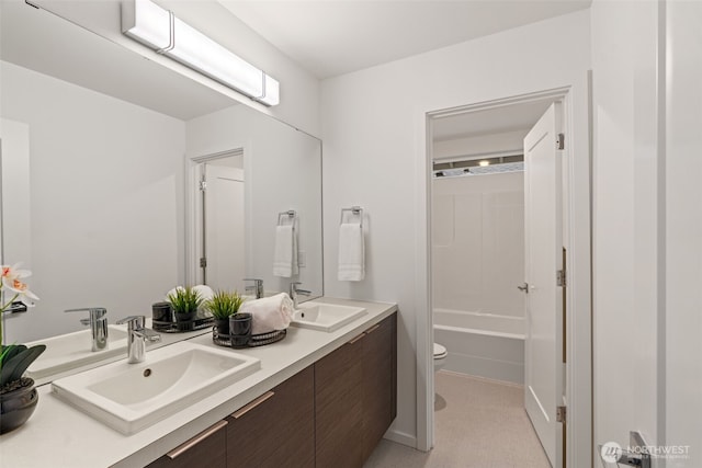 bathroom featuring shower / bathtub combination, double vanity, a sink, and toilet