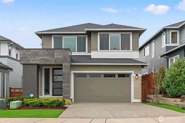 view of front facade with a garage, concrete driveway, a shingled roof, and fence