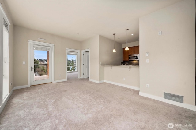 unfurnished living room featuring light carpet, baseboards, and visible vents