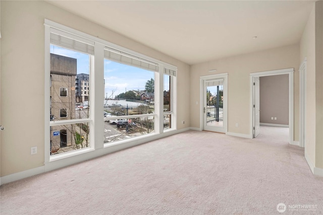 spare room with baseboards and light colored carpet