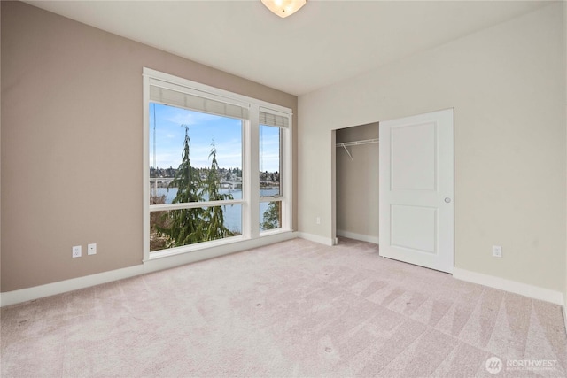 unfurnished bedroom featuring a water view, light carpet, and baseboards