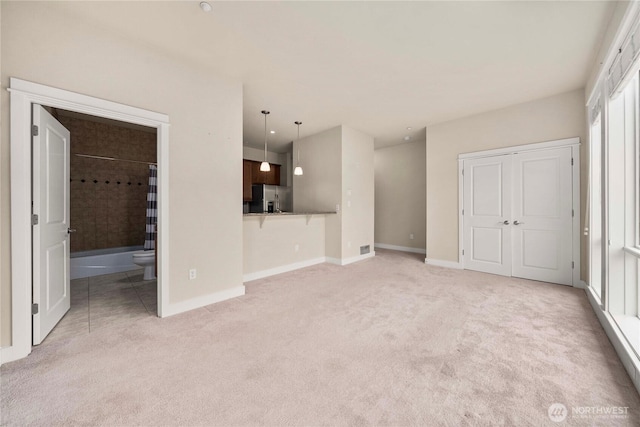 unfurnished living room featuring light carpet and baseboards