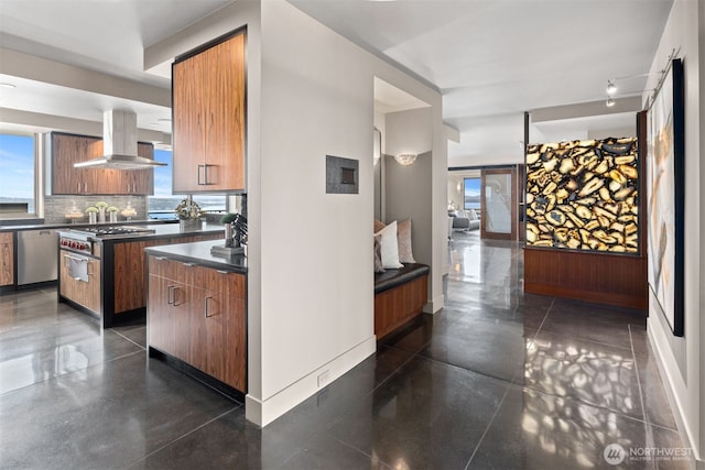 kitchen featuring tasteful backsplash, island range hood, brown cabinetry, dishwasher, and dark countertops