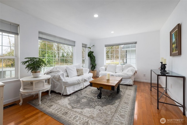 living area with visible vents, baseboards, wood finished floors, and recessed lighting