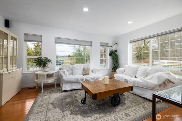 living area featuring recessed lighting, visible vents, and wood finished floors