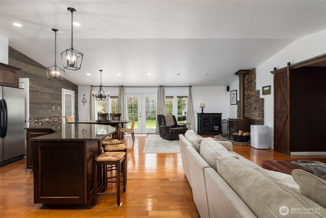 living area featuring lofted ceiling, light wood finished floors, a barn door, and recessed lighting