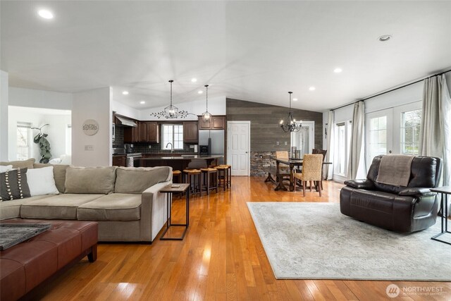 living room with lofted ceiling, french doors, light wood-type flooring, a chandelier, and recessed lighting