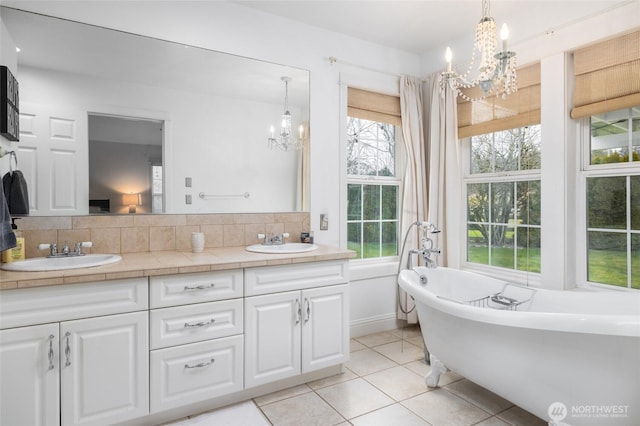 bathroom featuring a freestanding tub, a sink, decorative backsplash, and an inviting chandelier