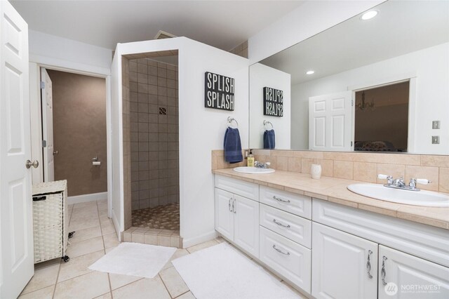 bathroom with a walk in shower, double vanity, a sink, and tile patterned floors