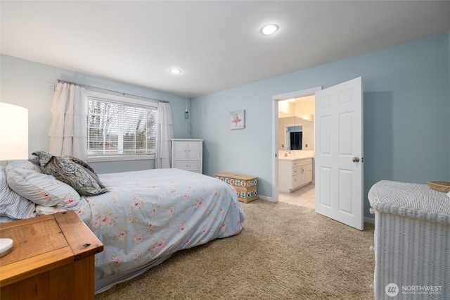 bedroom featuring recessed lighting, light colored carpet, connected bathroom, a sink, and baseboards